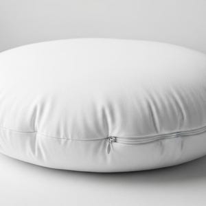 May include: A white, round floor pillow with a zipper closure. The pillow is made of a smooth, possibly synthetic material. The pillow is approximately 24 inches in diameter.