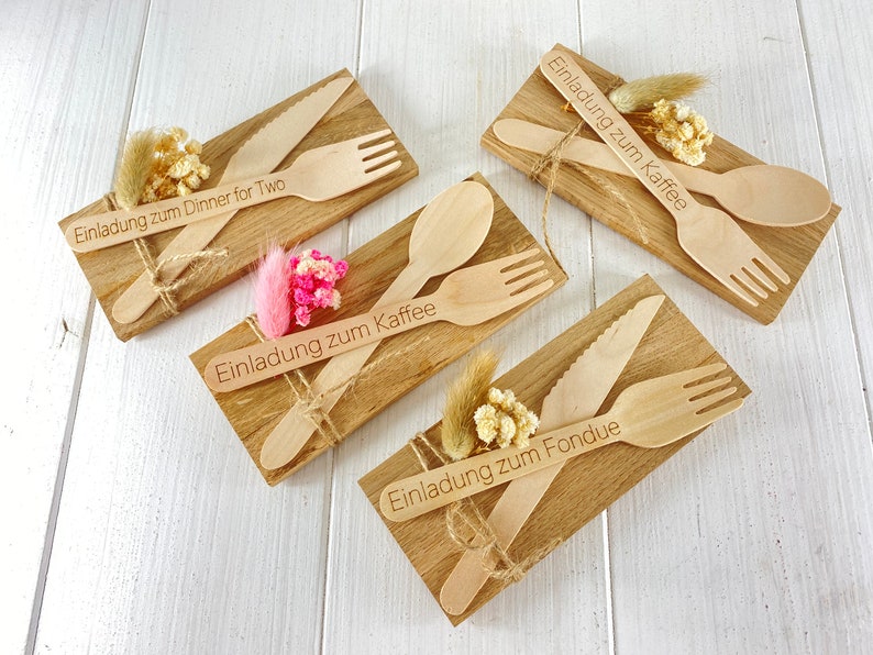 K&ouml;nnte beinhalten: Vier Holzbretter mit gravierten Einladungen und Holzbesteck. Die Einladungen lauten "Einladung zum Dinner for Two", "Einladung zum Kaffee", "Einladung zum Kaffee" und "Einladung zum Fondue".