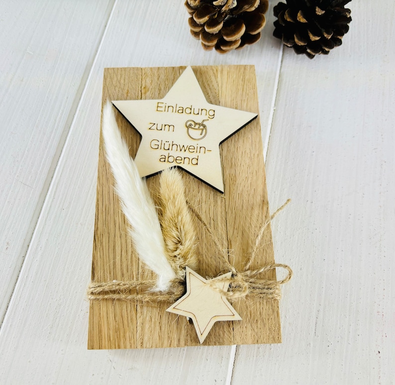K&ouml;nnte beinhalten: Eine Holz-Einladungskarte mit einem sternf&ouml;rmigen Holzschild, auf dem "Einladung zum Gl&uuml;hwein-abend" steht. Die Karte ist mit getrockneten Blumen und Schnur verziert.