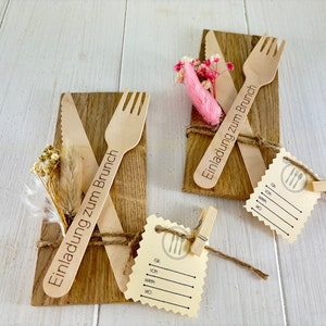 K&ouml;nnte beinhalten: Zwei Holz-Platzkarte mit dem Text "Einladung zum Brunch" (Einladung zum Brunch) und einer Holz-Gabel und einem Holz-Messer auf jeder. Die Platzkarte sind mit Schnur gebunden und mit getrockneten Blumen verziert. Es gibt auch eine leere Platzkarte mit einem Gabel- und Messer-Symbol.