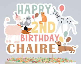 May include: Happy 2nd Birthday Chaire cake topper with a pink poodle, a cat, a ginger cat, a dalmatian, and a dachshund. The topper has colorful balloons and party hats.