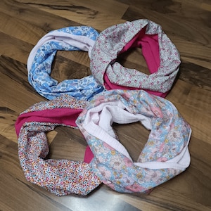 Peut inclure: Quatre foulards en tissu pour le cou avec des motifs floraux. Les foulards sont dans des tons de rose, bleu et blanc.