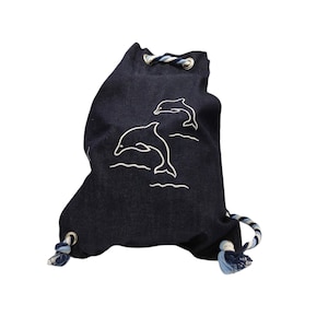 May include: A dark blue drawstring bag with white embroidered dolphins. The bag has a white and blue rope drawstring.