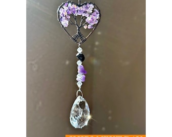 May include: A heart-shaped suncatcher with a wire tree design filled with purple gemstones. The suncatcher hangs from a chain and features a teardrop-shaped crystal pendant at the bottom. The suncatcher is a decorative item.