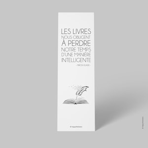 Peut inclure: Signet noir et blanc avec une citation en français sur les livres et le temps. La citation est "Les livres nous obligent à perdre notre temps d'une manière intelligente -Mircea Eliade-". Le signet présente une illustration stylisée d'un livre ouvert avec une plume.