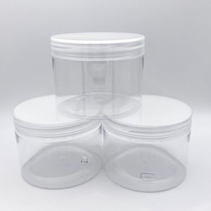 May include: Three clear plastic jars with white screw-on lids are stacked on a white background. The jars are cylindrical and appear empty. The lids are flat and smooth. The jars are likely for storing items.