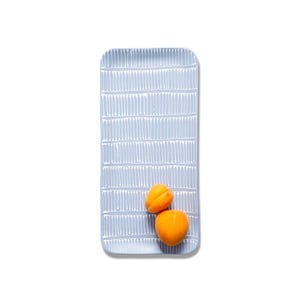 Könnte beinhalten: Ein rechteckiges, hellblaues Serviertablett mit einem Muster aus vertikalen, weißen, gestrichelten Linien. Zwei runde, orangefarbene Aprikosen liegen auf dem unteren Teil der Tablettfläche. Das Tablett hat abgerundete Ecken und ein flaches Design.
