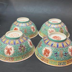 May include: Four antique Chinese porcelain bowls. Each bowl features a turquoise background with colorful floral and geometric patterns, and Chinese characters. The bowls have a scalloped edge and a white interior. A decorative and collectible item.