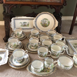 May include: A vintage tea set featuring a birch tree design. The set includes a teapot, sugar bowl, creamer, and a selection of cups and saucers.