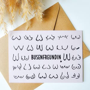 Könnte beinhalten: Eine weiße Karte mit schwarzen Strichzeichnungen von Brüsten in verschiedenen Formen. In der Mitte steht das Wort "BUSENFREUNDIN". Die Karte liegt auf einem braunen Umschlag, im Hintergrund getrocknete Pflanzen.