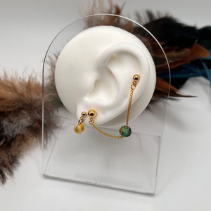 Op de afbeelding: Gouden ketting oorring met een groene en witte kraal en een gele kraal. De oorring wordt getoond op een wit oormodel.