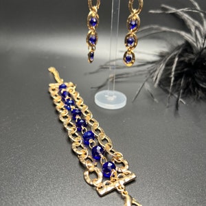 May include: A gold chain bracelet with blue crystal beads and matching gold chain earrings with blue crystal beads.