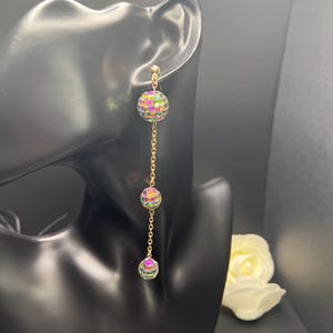 May include: Gold dangle earrings with three iridescent rainbow colored ball charms.