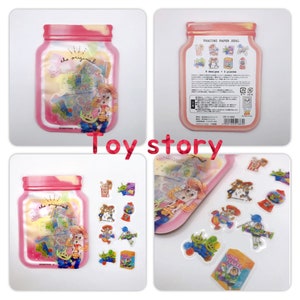 May include: A set of 8 Toy Story themed stickers in a clear plastic jar with a pink lid. The stickers feature characters from the movie, including Woody, Buzz Lightyear, and the aliens. The jar has the text "the original" on it.