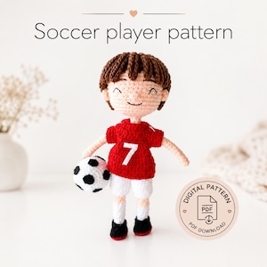 May include: A crocheted doll of a soccer player with brown hair, wearing a red jersey with the white number 7, white shorts, and black shoes, holding a black and white soccer ball. The text Soccer player pattern and Digital pattern PDF appear.