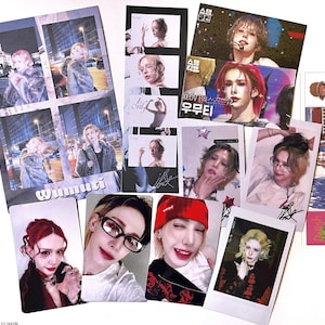 May include: A collection of K-pop fan merchandise, including photo cards and a poster. The photo cards feature various images of a person with different hairstyles and expressions. The poster has multiple images of the same person in a city setting.