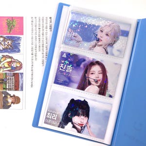 May include: A blue binder with three clear plastic photo card holders. Each holder features a different K-pop idol with a holographic background and text that reads "Fancam" and "Virtual Angel".