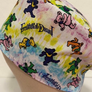 May include: A tie-dye fabric scrub hat with a Grateful Dead logo and dancing bear print. The hat is white with pink, blue, yellow, and green tie-dye patterns.