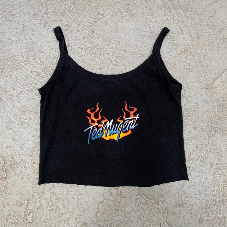 May include: Black sleeveless crop top with a graphic print of flames and the text "Ted Nugent".
