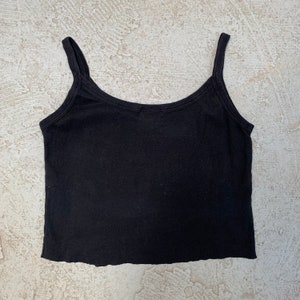May include: A black sleeveless cropped tank top with a scoop neck.