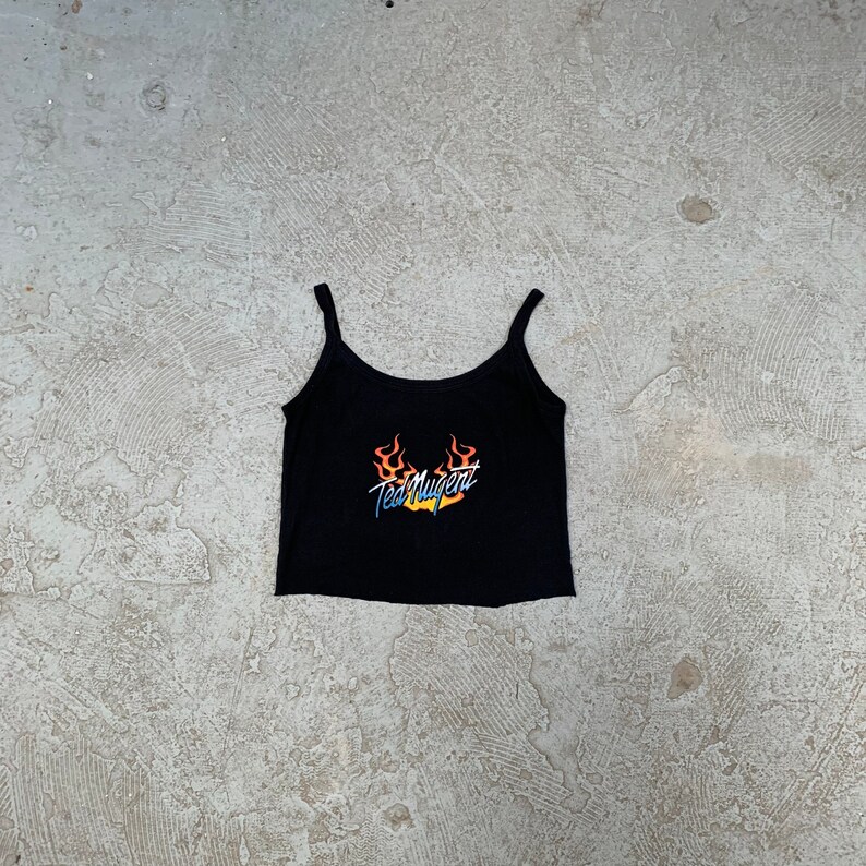 May include: Black spaghetti strap tank top with a graphic print of flames and the text "Ted Nugent".