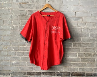 May include: Red and white striped baseball jersey with the text "Chicago Bulls" on the front. The jersey has a button-up front and short sleeves.