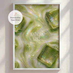 Pode incluir: Impressão emoldurada com um close-up de uma bebida matcha com cubos de gelo. A bebida tem uma aparência verde leitosa e rodopiante com o texto "Matcha Girl" no centro. Uma moldura branca envolve a imagem.