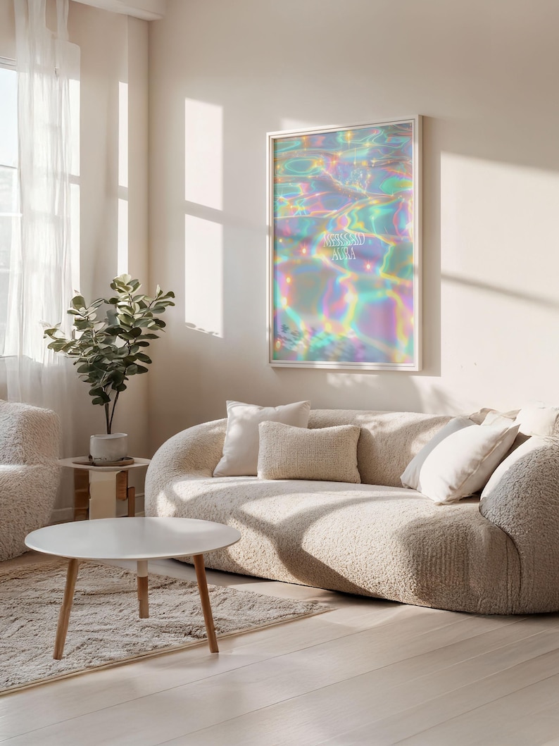 Pode incluir: Uma impress&atilde;o de arte de parede emoldurada com um design abstrato iridescente com as palavras "Blessed Aura" em branco. A obra de arte est&aacute; pendurada acima de um sof&aacute; curvo creme com almofadas a condizer. Uma mesa de centro redonda e branca e uma pequena planta em vaso tamb&eacute;m s&atilde;o vis&iacute;veis.