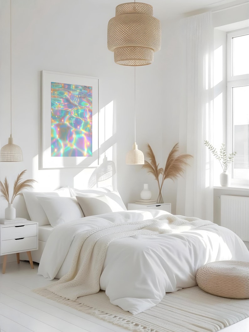 May include: A bright, airy bedroom with white bedding, a framed art print, and woven pendant lights. The art print features a colorful, iridescent water reflection. The room includes a white rug, nightstands, and a neutral-toned ottoman, creating a serene atmosphere.