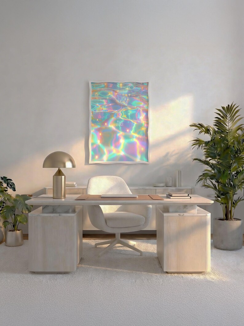 May include: A rectangular wall art print featuring a vibrant, iridescent water surface with shimmering rainbow light reflections in shades of blue, pink, and yellow, displayed in a white frame above a desk in a bright room.
