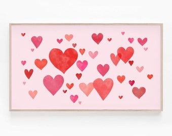May include: A pink background with a framed print of watercolor hearts in shades of red and pink.