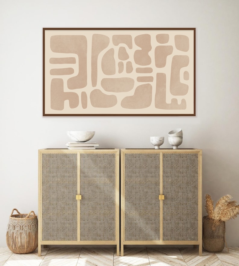 Puede incluir: Una impresi&oacute;n de arte abstracto beige con marco marr&oacute;n cuelga sobre dos armarios de madera con puertas de ca&ntilde;a tejida. Los armarios tienen herrajes dorados y est&aacute;n sobre un suelo de madera con un patr&oacute;n de chevron.