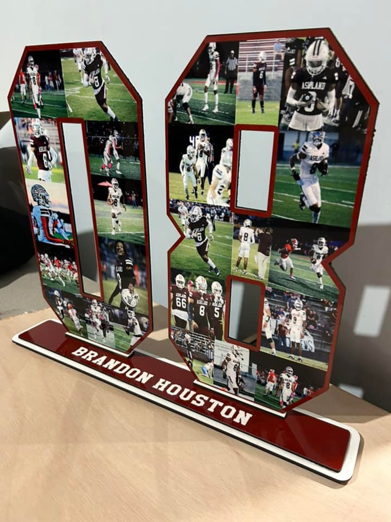 Puede incluir: Un n&uacute;mero 8 de madera rojo y blanco con un collage de fotos de un jugador de f&uacute;tbol americano con un uniforme granate y blanco. La base del n&uacute;mero es roja con letras blancas que dicen "BRANDON HOUSTON".