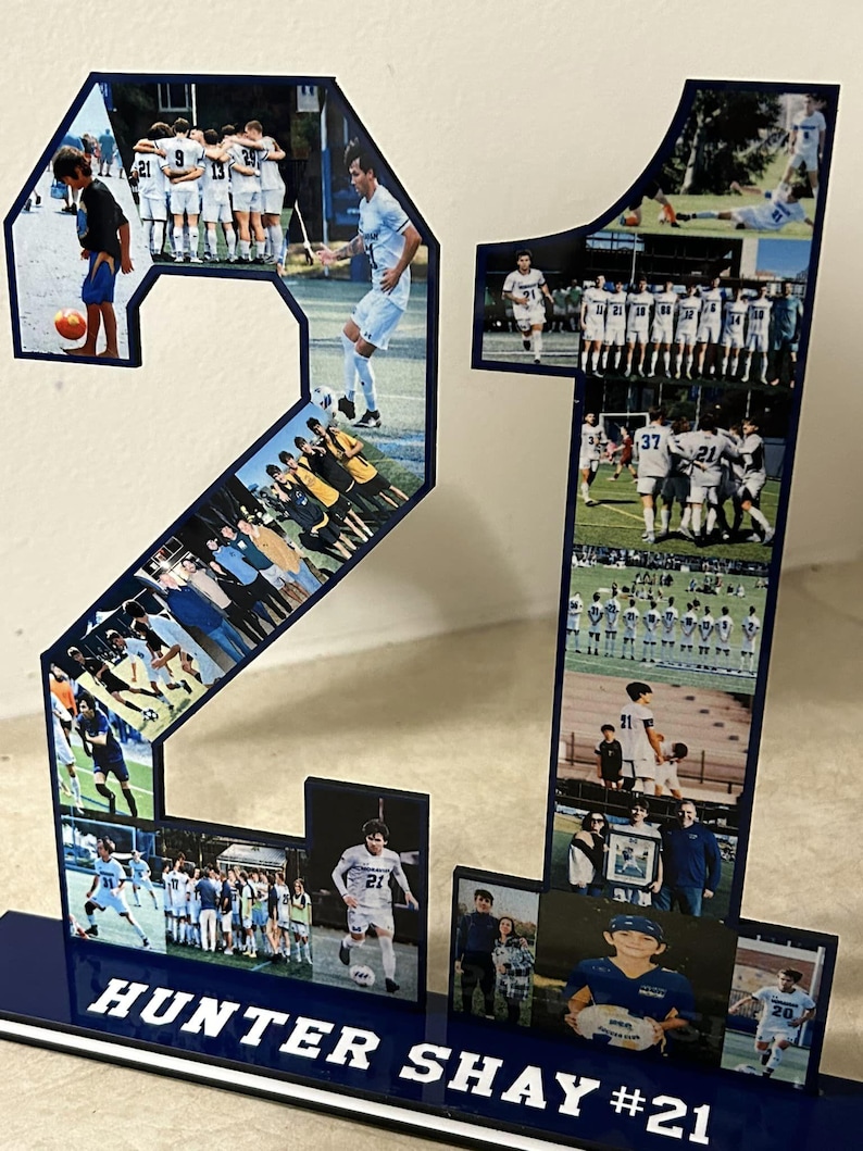 Puede incluir: Un n&uacute;mero 21 azul y blanco hecho de acr&iacute;lico con fotos de un jugador de f&uacute;tbol y un equipo. La base del n&uacute;mero es azul con letras blancas que dicen "HUNTER SHAY #21".