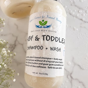 Könnte beinhalten: Eine durchsichtige Kunststoff-Pumpflasche mit beigem Baby- und Kleinkind-Shampoo und Waschgel. Das Etikett zeigt Nature's Extract for Natural Beauty, Skin And Mind Divine, Baby & Toddler Shampoo + Wash, net wt. 228g, bedeckt mit Wassertropfen.