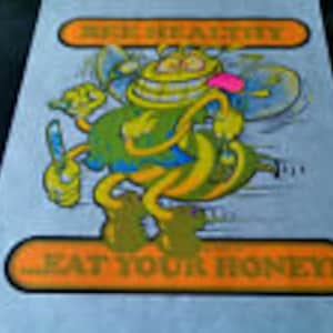 May include: A cartoon bee with a big smile and a pink flower on its head. The bee is wearing a green and yellow outfit and is flying with its wings spread out. The text "Be Happy" is above the bee and the text "Eat Your Honey" is below the bee.