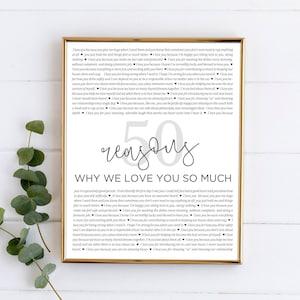 May include: A printable poster with a black and white design. The poster features the text "50 reasons why we love you so much" and a list of reasons why someone is loved. The poster is framed in a gold frame.