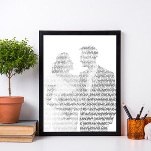 May include: A black framed print with a white background. The print features a silhouette of a couple, formed by a dense arrangement of text. The text is in a small font size and is difficult to read. The print is displayed on a white shelf with a small potted plant, a pencil holder, and a small elephant figurine.