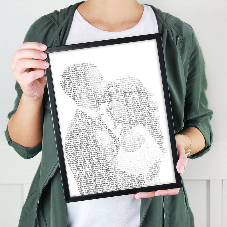 May include: Black and white typography art print featuring a silhouette of two people embracing. The print is made up of song lyrics, including the phrase "Your love is moving mountains".