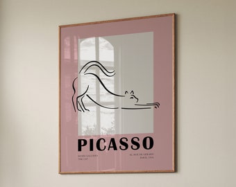 May include: A pink framed poster with a black line drawing of a cat stretching. The poster has the text "PICASSO" in black letters and the text "MUSEE GALLIERA THE CAT" and "42 RUE DE GERARD PARIS, 1936" in smaller black letters.