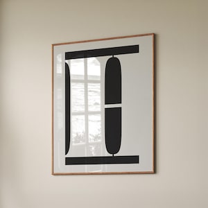 May include: A framed abstract art print featuring a minimalist design. The artwork showcases bold black shapes against a white background, with a wooden frame. The design includes horizontal and vertical lines and rounded shapes.