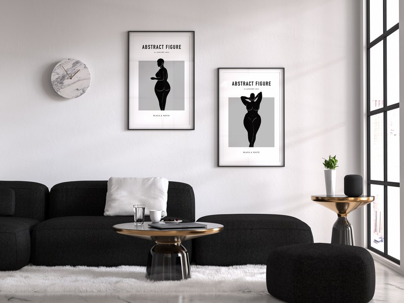Pu&ograve; includere: Due stampe artistiche in bianco e nero incorniciate con la scritta "ABSTRACT FIGURE" e la silhouette di una donna. Le stampe sono appese a una parete bianca sopra un divano e un tavolino neri. Un orologio in marmo &egrave; sulla parete.