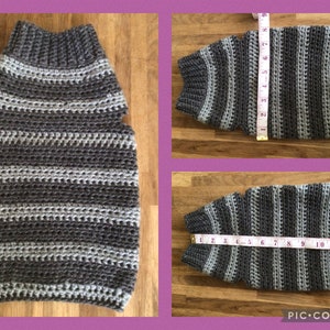 May include: A gray and white striped crocheted dog sweater with armholes. The sweater is laid flat on a wooden surface with a measuring tape next to it.
