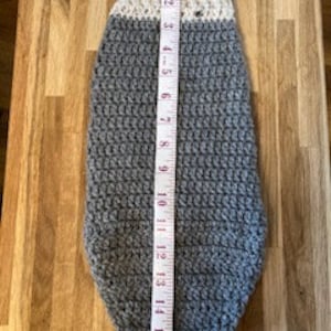 May include: Gray crocheted dog sweater with a white crocheted collar. The sweater is 16 inches long.