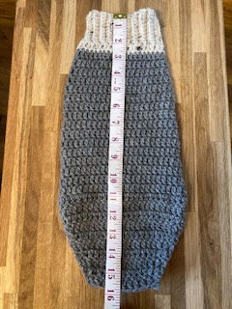 May include: Gray crocheted dog sweater with a white crocheted collar. The sweater is 16 inches long.