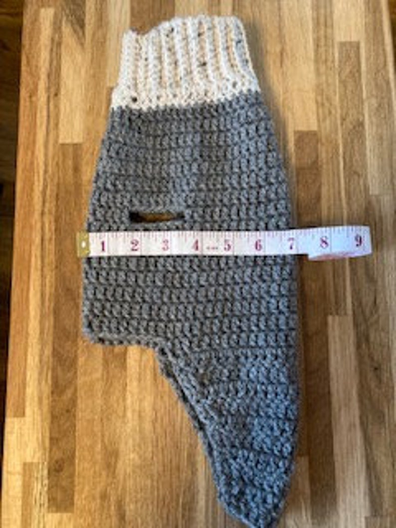 May include: Gray and white crocheted dog sweater with a hole for the leash. The sweater measures 9 inches across.