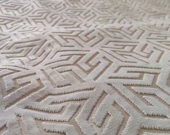 May include: Close-up of a white textured fabric with a geometric pattern. The pattern is made up of repeating squares and triangles.