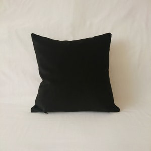 May include: A black square pillow with a zipper closure.