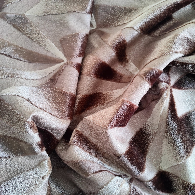 Op de afbeelding: Close-up van een bruine en beige stof met een geometrisch patroon. De stof heeft een zachte, pluche textuur.