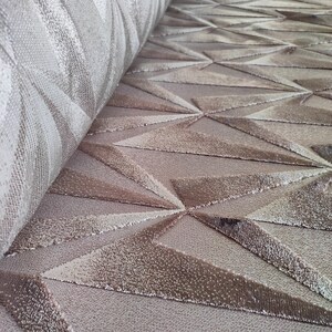 Op de afbeelding: Close-up van een beige tapijt met een geometrisch patroon van reli&euml;f driehoeken. Het tapijt heeft een zachte, pluche textuur.